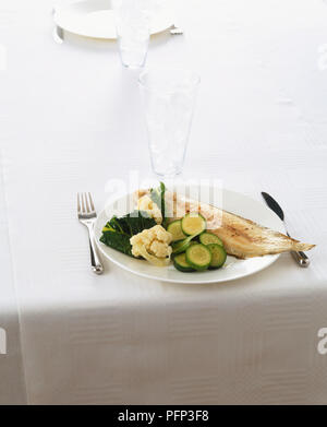 Gegrillte Weißfischfilet auf weißer Keramik Platte mit gedünsteten Blumenkohl Röschen, kohlblatt serviert und in Scheiben geschnittenen Zucchini Stockfoto