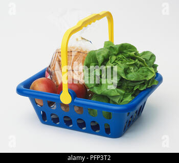 Blauer Korb mit gelber Griff, mit roten Äpfeln, geschnittenem Brot in Kunststoff und Leiter des Kopfsalates gewickelt. Stockfoto