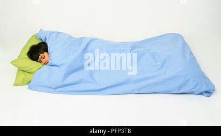 Junge im Bett lag, mit blauen Bettdecken abgedeckt Stockfoto