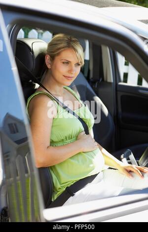 Schwangere Frau im Auto auf den Sicherheitsgurt, Seitenansicht Stockfoto