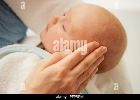 Woman's Hand reiben Baby Öl in die Kopfhaut, close-up Stockfoto