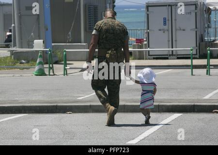 Sgt. Maj. Marcos A. Cordero, auf-kommenden Sergeant Major für 3 Reconnaissance Bataillon, 3rd Marine Division, dauert ein Spaziergang mit seiner Tochter vor der Änderung des Befehls Zeremonie, 25. Mai 2018 auf Lager Schwab, Okinawa, Japan. Cordero übernahm Aufgaben als 3. Aufklärung Sergeant Major nach Verlassen der dritten Bataillon, 12 Marine Regiment, 3rd Marine Division und Sgt. Maj. misenhimer ist schiefergedeckt, Aufgaben als Sergeant Major des 12 Marines zu übernehmen. Misenhimer unterstützt der dritten Aufklärungsmission Boden und amphibische Aufklärung und Überwachung sowie zur Durchführung von anderen Maßnahmen zur Unterstützung der 3. Stockfoto