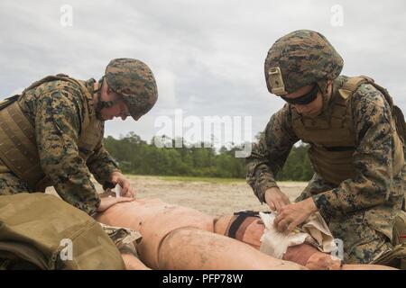 Petty Officer 2nd class Anna Raykiewicz, Hospital corpsman, 22 Marine Expeditionary Unit, gilt ein stauschlauch bei einem simulierten Unfall während einer taktischen Evakuierung Kurs in Camp Lejeune, N.C., 23. Mai 2018. Die taktische Evakuierung Kurs ausgebildet Hospital corpsman die korrekten Techniken in ungewöhnlichen Evakuierung Umgebungen zu verwenden. Stockfoto