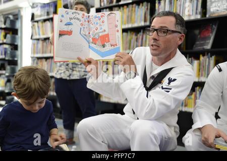 BROOKLYN, NY (24. Mai 2018) Feuer Controlman 2. Klasse Brian Keenan, aus Philadelphia, liest für Kinder in der Brooklyn Public Library während der Fleet Week 2018. Jetzt in seinem 30. Jahr, Fleet Week New York ist die Stadt der altehrwürdige Feier auf das Meer. Es ist eine einmalige Chance für die Bürger von New York und die umliegenden Tri-state-Area zu treffen Seemänner, Marinesoldaten und Küstenwache sowie Zeugnis aus erster Hand die neuesten Funktionen der heutigen Maritime Services. Stockfoto