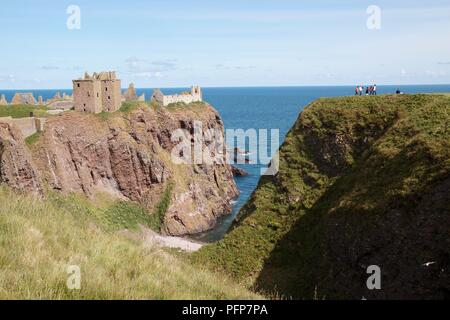 Schottland Stonehaven, Dunnottar Castle, Reste der mittelalterlichen Burg auf der felsigen Landzunge und Gruppe von Menschen auf der gegenüberliegenden Felsen Stockfoto