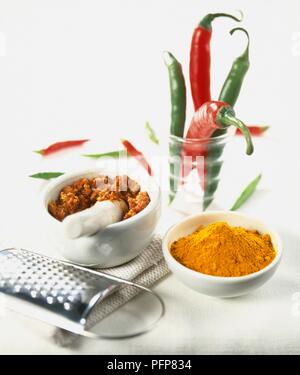 Boden Kurkuma, gemahlen Gewürze in Mörtel und ganze Grüne und rote Paprika in Glas Stockfoto