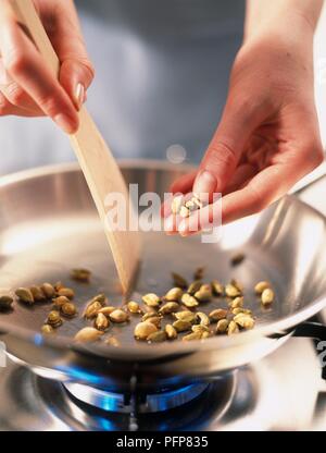 Hinzufügen von kardamomen in der Pfanne, Rühren mit Holzspachtel, close-up Stockfoto