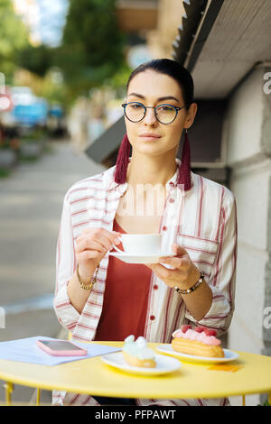 Selbstbewusste Frau essen Desserts und Kaffee trinken Stockfoto