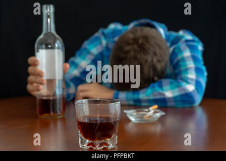 Man Alkohol trinken und rauchen eine Zigarette in ihrem Haus auf dem Tisch, selektiver Fokus, dunkles Bild, sucht Konzept Stockfoto