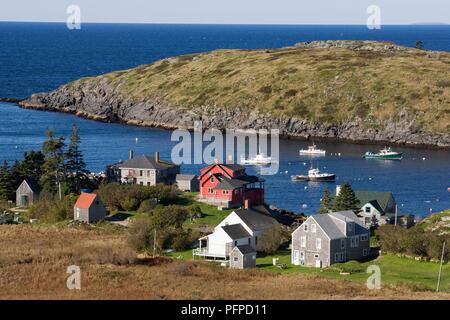USA, Maine, Monhegan Island, Häuser im Hafen, Boote im Kanal, und Manana Island im Hintergrund Stockfoto
