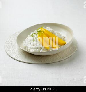 Klebreis mit Mango slices in Weiß Schüssel serviert auf Unterlage Stockfoto