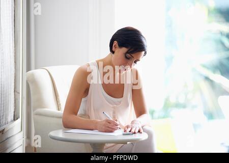 Frau sitzt am Tisch, schreiben Stockfoto