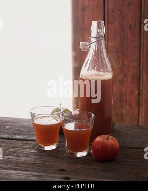 Flaschen und Gläsern hausgemachter Apfelsaft, und einen frischen Apfel Stockfoto