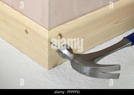 Hämmern Nagel in Holz Sockelleiste, in der Nähe Stockfoto