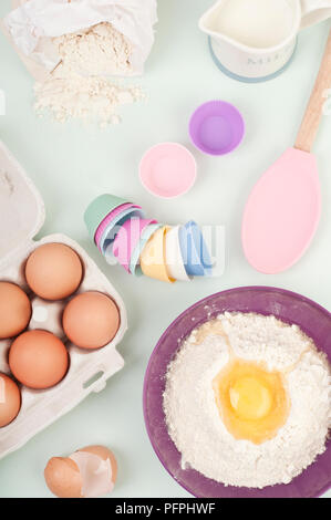 Backen Zutaten und Utensilien, inklusive Box der Eier, Ei Mehl in eine Schüssel geben, Fälle für Cupcakes Stockfoto