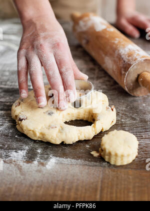 Mit dem Fräser die Scones auf bemehlten Oberfläche zu schneiden, Rolling Pin in der Nähe Stockfoto