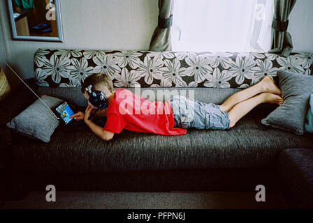 9 Jahre alter Junge mit seinem Tablet Sofa, Kingsbridge, Devon, England, Vereinigtes Königreich. Stockfoto