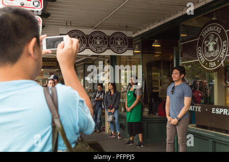 Die Besucher nehmen Bilder vor der ursprünglichen Logo bedruckt Fenster Kaffee von Starbucks Flagship Store am Pike Place Market in Seattle, Washington, USA. Stockfoto