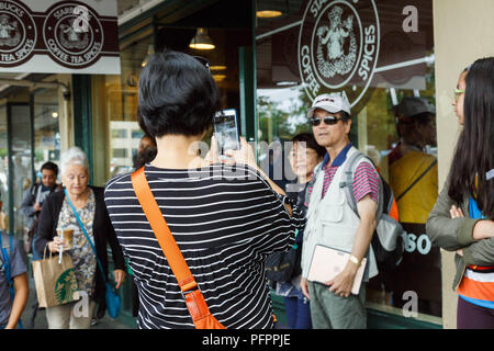 Die Besucher nehmen Bilder vor der ursprünglichen Logo bedruckt Fenster Kaffee von Starbucks Flagship Store am Pike Place Market in Seattle, Washington, USA. Stockfoto