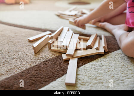 Wenig kaukasische Mädchen sitzen auf dem Teppich und Spiel, Entwicklung Spielzeug, Prozess Stockfoto