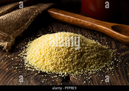 Haufen rohe, Ungekochte couscous auf hölzernen Tisch Hintergrund Stockfoto