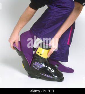 Junger Mann auf Ski Stiefel Stockfoto