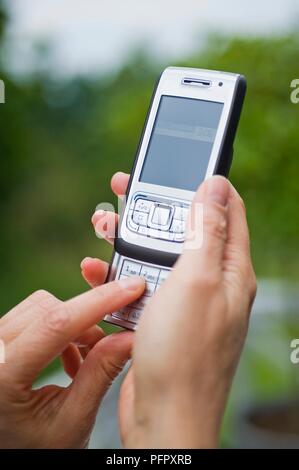 Hände, die Mobiltelefon und über die Tastatur Stockfoto