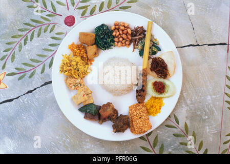 Nasi Campur (Gemischter Reis) serviert mit Erdnüssen, Spiegelei, Tofu, gebratenes Huhn, Satay, gedämpftem Reis, Gurken, frittierte Sojabohnen Stockfoto