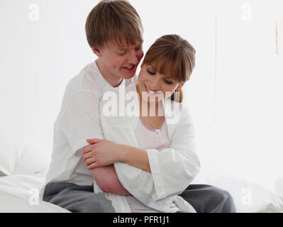 Junge Mann hinter eine junge Frau sitzt, seine Arme um ihre Stockfoto