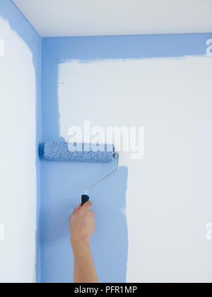 Mann mit Paint roller weiße Wände blau zu malen, close-up Stockfoto