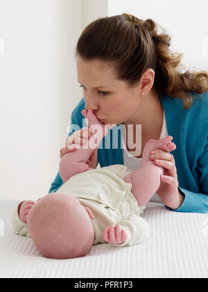 Frau küssen Baby boy Füße (6 Wochen). Stockfoto