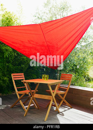 Rote Garten sail Schattenspender für Holz- Tisch und Stühle auf, überdachte Terrasse im Garten Stockfoto