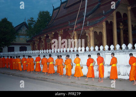 Laos, nördlichen Laos, Luang Prabang (Luang Phabang), buddhistische Mönche auf tägliche Almosen Runde auf Thanon Sisavangvong Straße, Dawn Stockfoto