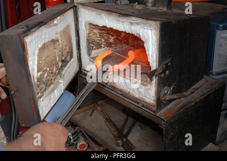 Schmied Entfernen von Red Hot Hufeisen aus mittels Zange schmieden, close-up Stockfoto