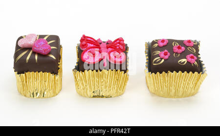 Kleine Schokolade Kuchen mit rosa Zuckerguss, in gold Kuchen Fällen Stockfoto