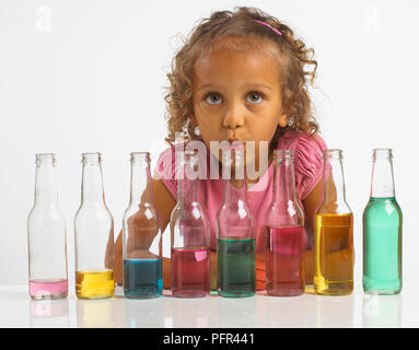 Mädchen spielen 'Flasche', Schlag in Flasche, ist Teil einer Reihe von Flaschen mit verschiedenen Mengen von Wasser, 4 Jahre gefüllt Stockfoto