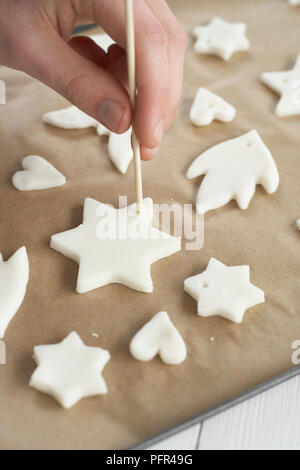 Piercing Loch in Lebkuchen Kekse, zu Weihnachten Dekorationen machen Stockfoto