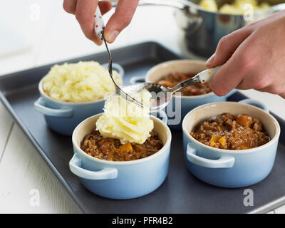 Einzelnen cottage Pies, Hinzufügen von Mash potato in Förmchen Stockfoto