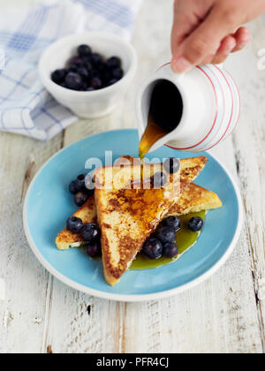 Gießen Ahorn Sirup über Nelly Brot und Blaubeeren Stockfoto