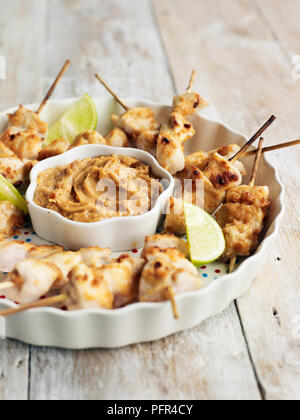 Hähnchenteile auf Spieße mit Satay Sauce in runde Teller serviert. Stockfoto