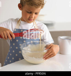 Junge rühren Pfannkuchenteig in eine Schüssel, 6 Jahre Stockfoto