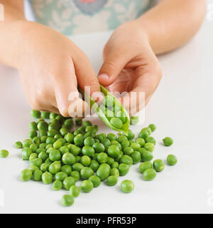 Mädchen Erbsen drücken aus einem Pod Stockfoto