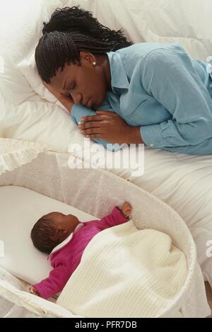 Liegende Frau auf dem Bett schlafen Neben Baby Moses Korb Stockfoto