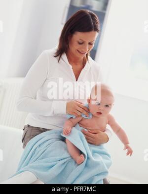 Frau sitzt mit vier Monate alten Baby auf dem Schoß in Handtuch aus der Hüfte nach unten Stockfoto