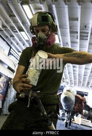 Lance Cpl. Garrett Gudauskas, zugeordnet zu den Marine Medium Tiltrotor Squadron (VMM) 162 (verstärkt), bereitet den Lack im Hangar Bay an Bord der Wasp-Klasse amphibisches Schiff USS Iwo Jima (LHD7), 22. Mai 2018. Iwo Jima in Mayport, Fla., ist homeported in die USA 5 Flotte Bereich für Maßnahmen zur Erhöhung der Sicherheit im Seeverkehr im Einsatz Verbündeten und Partnern zu beruhigen, und der Freiheit der Schiffahrt und des freien Handels in der Region erhalten. Stockfoto