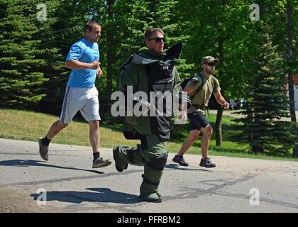 Us Air Force Senior Airman Ethan Johnson, ein 119 Flügel die Beseitigung von Explosivstoffen (EOD) Techniker, joggt während eines 5K laufen, tragen ein 80 Pound" Bombe Schutz suit' in der Nähe des Sees von Ida, Minn., 26. Mai 2018. Johnson ist sich der schwere Gang auf der Flucht Geld für wohltätige Zwecke. Er ist der dritte Mitglied seiner Texas Air National Guard EOD Funktionsbereich ein 5k in der Bombe Schutzanzug in drei Jahre laufen. Staff Sgt. Nick Verdi, ein Feuerwehrmann in der 119 Bauingenieur Squadron, joggt mit einem Ruck sack zu seiner Rechten, und Corp. Ryan Oliver, der 1-194 C-Batterie, Minn. Army National Gua Stockfoto