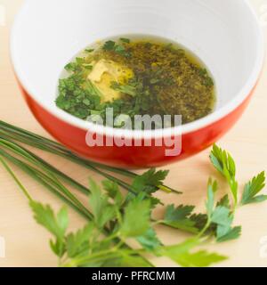 Schüssel Salat Dressing mit Olivenöl, Senf, Pesto und gehackte Petersilie, frische Petersilie neben der Schüssel Stockfoto