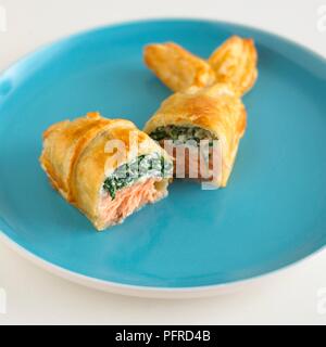 Fischförmige Blätterteig in der Hälfte mit Spinat und Lachs anfüllen, die auf einem blauen Platte Stockfoto