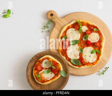 Zwei pizzas überbacken mit Mozzarella, Tomaten, Basilikum und Thymian, auf Holztafeln Stockfoto