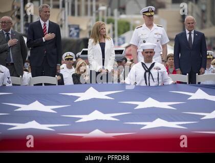 NEW YORK (28. Mai 2018) Von links, Bruce Mosler, Intrepid Museum Co-vorsitzender; Bürgermeister von New York, Bill De Blasio; Susan Marenoff-Zausner, Intrepid Museum Präsident; Adm. Christopher Grady, Commander, US-Flotte Kräfte und Mel Immergut, Intrepid Museum Stellvertretender Vorsitzender watch US-Mitglieder und Veteranen entfalten eine amerikanische Flagge zu einem Memorial Day Feier auf der Intrepid Sea, Air & Space Museum in New York City während der Fleet Week New York 2018. Jetzt in seinem 30. Jahr, Fleet Week New York ist die Stadt der altehrwürdige Feier auf das Meer. Es ist eine einmalige Chance für die citize Stockfoto